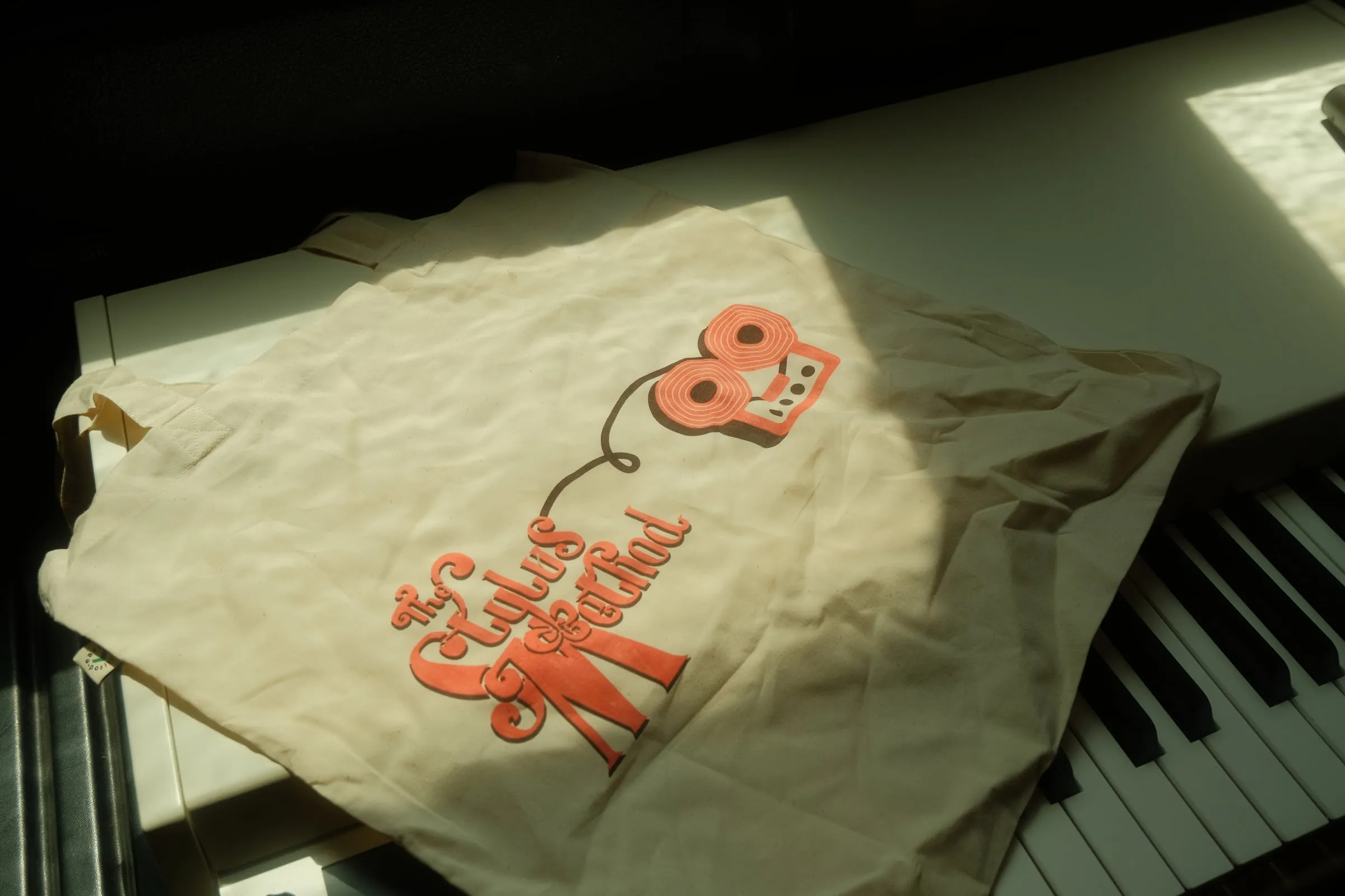 The Stylus Method tote bag lying on a piano